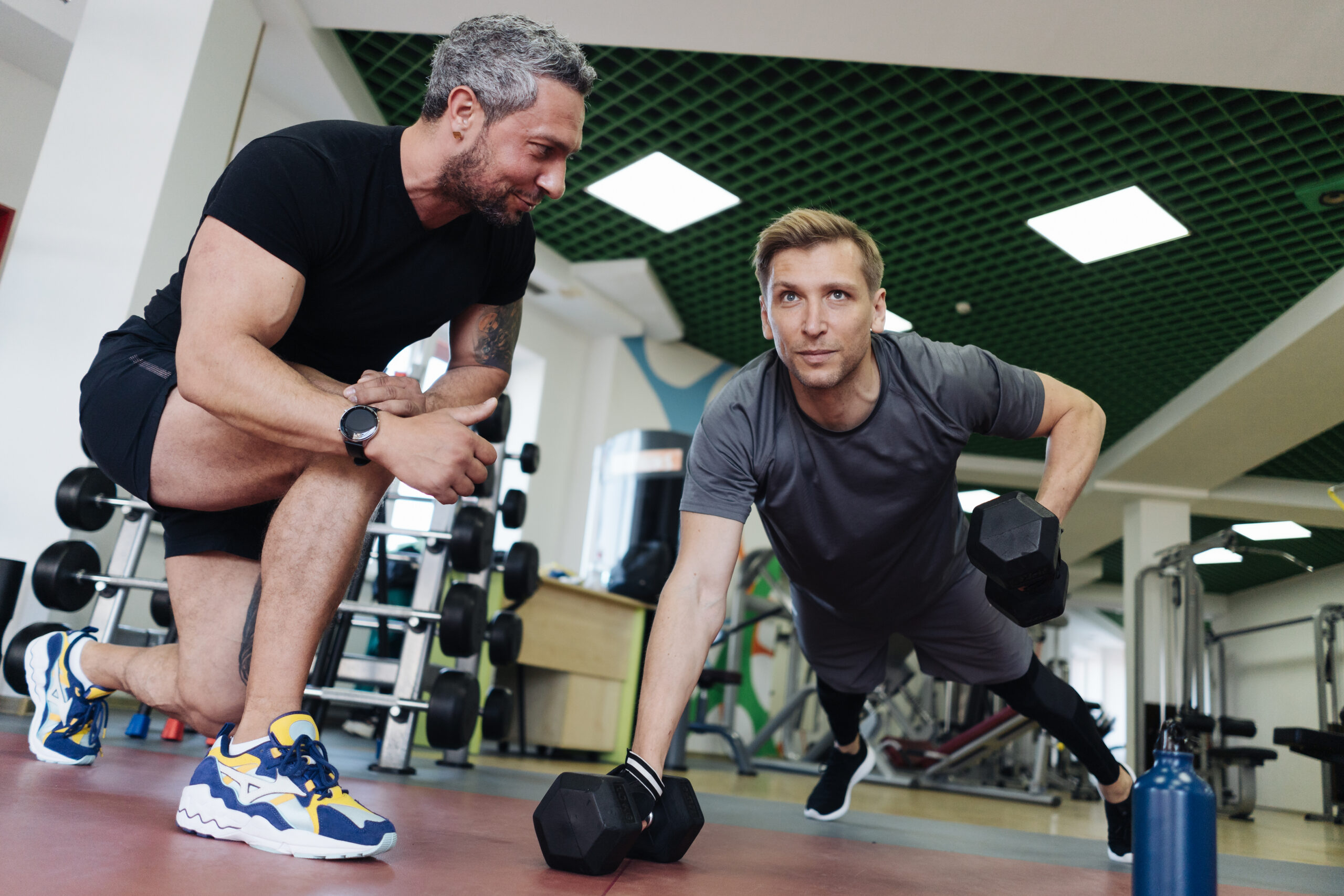 A personal trainer motivates the client to do push-ups in the gym. Personal workout hour with personal coach